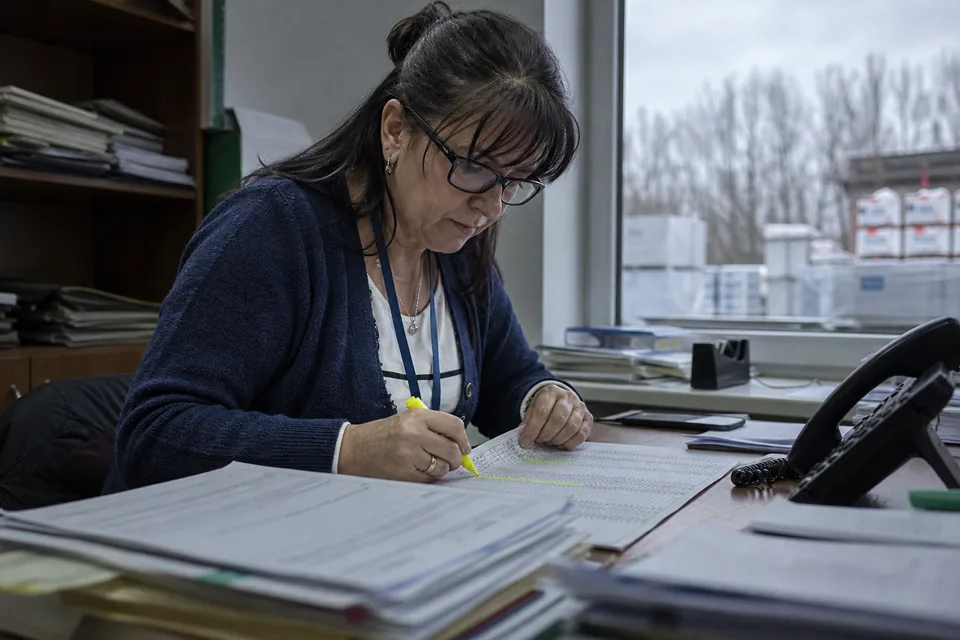 Kierowniczka finansów zaznacza pozycje na wydruku listy kontrahentów